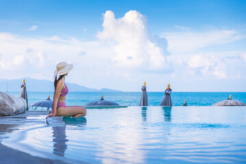 Asian traveler bikini woman relax and travel in infinity pool resort at Koh Samui beach Thailand