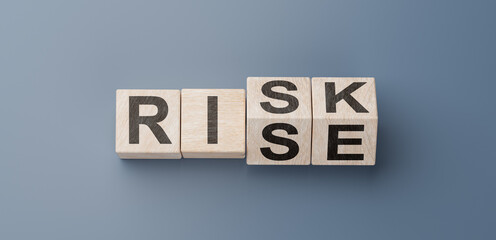 cubes turning message RISK to RISE. Turned wooden cubes with words Risk vs Rise. Blue background. Business and Rise vs Risk concept