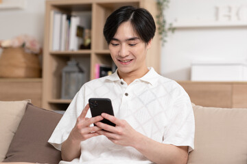 Asian man is smiling on the cellphone like he got a good news. The man seems so happy with the...