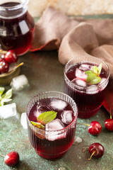 Cold refreshing cherry cola in a glass with ice on a stone background, summer juice. Copy space.
