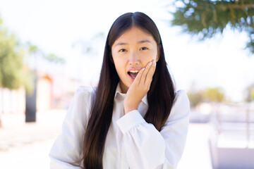 Pretty Chinese woman at outdoors surprised and shocked while looking right