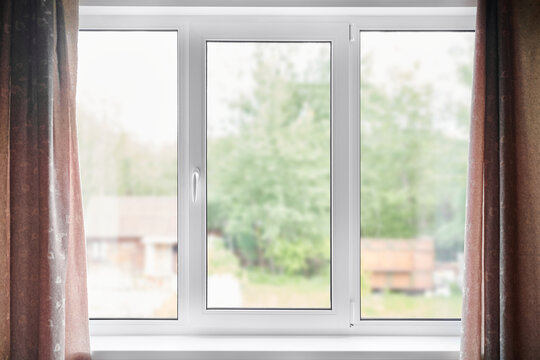 Fototapeta Closed plastic window and wall inside the room. Window with view of summer sunny backyard of wooden country house.