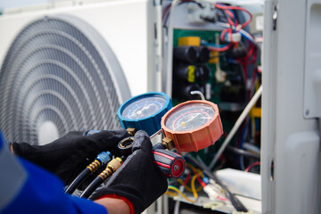 air conditioner technician using manifold gauge checking refrigerant for filling home air conditioning and air duct cleaning and maintenance outdoor compressor unit. - obrazy, fototapety, plakaty