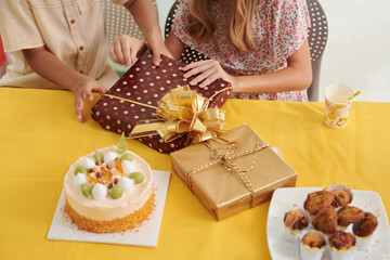 Kids unwrapping birthday presents at party, view from above
