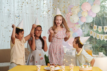 Group of kids jumping under falling confetti at birthday party