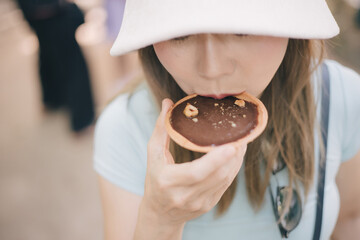 Woman standing and eating chocolate tart