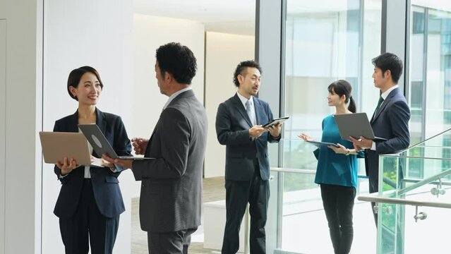 デジタルデバイスを持って打ち合わせするビジネスパーソンのグループ