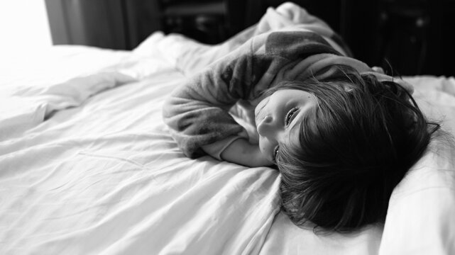 little girl in pajamas lying on the bed, family relations, horizontal format, black and white photo