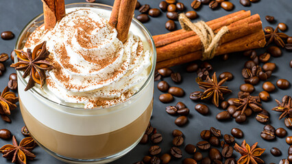 caffe latte with whipped cream, cinnamon and anise in a glass