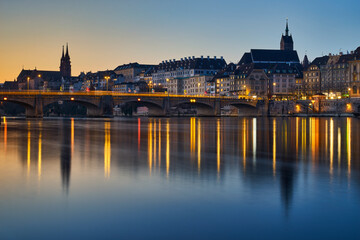 Fototapeta na wymiar Frühmorgens in Basel bei der Mittleren Brücke. Kurz nach der blauen Stunde werden die Brückenbögen und die Altstadt von der Sonne angestrahlt
