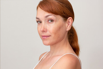 Portrait of cropped caucasian middle aged woman face with freckles on white background