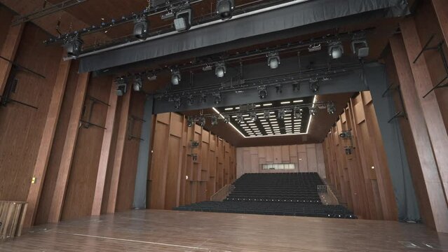 View from the stage to the empty auditorium. Modern concert hall made of wood. Modern stage equipment. Dolly camera