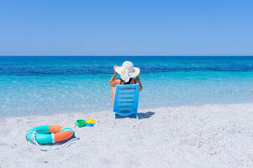 girl with white straw hat relaxes in front of the sea of ​​is arutas beach in central sardinia.