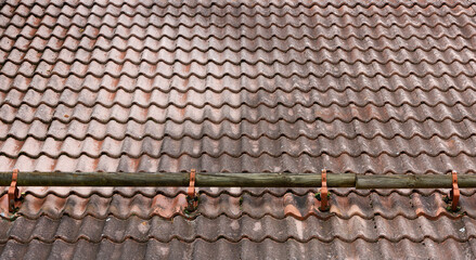 Brown profile roof installed on a house. The roof of corrugated sheet. Roofing of metal profile wavy shape. Modern roof with snow protection barrel