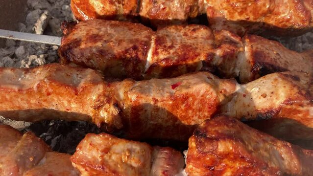 Grilling shashlik kebab on barbecue grill outdoors. Preparing juicy meat kebab on skewer in smoke. BBQ. Grill outdoors. Picnic time