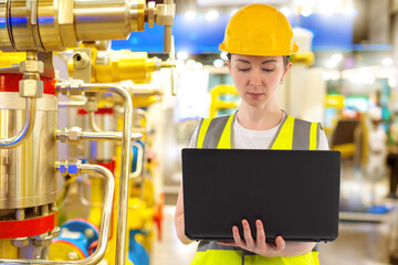 Woman works in factory. Factory manager with laptop. Industrial engineer. Production control via computer. Woman near industrial equipment. Factory technologist in helmet. Technician, contractor