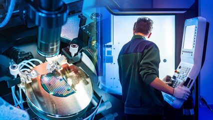 Production of digital boards. Microchip making machine. Factory worker with back to camera. Man controls production of digital circuit boards. Industrial equipment. Manufacturing of digital boards