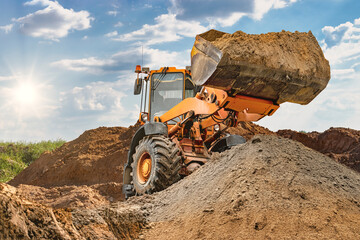 Wheel front loader bulldozer pours sand. Distributes sand for road construction. Powerful...