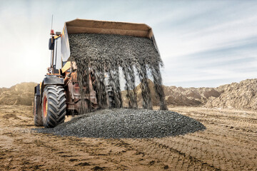 Wheel front loader pours crushed stone or gravel. Spreads crushed stone or gravel with a wide...