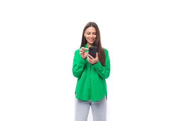 young caucasian brunette lady with make-up dressed in an elegant green shirt is chatting in a smartphone