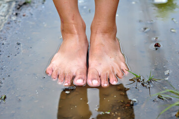 The child's feet are in a puddle of rain selective focus