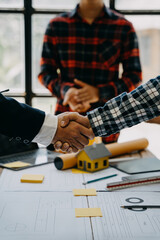 Construction workers, architects and engineers shake hands while working for teamwork and cooperation after completing an agreement in an office facility, successful cooperation concept.