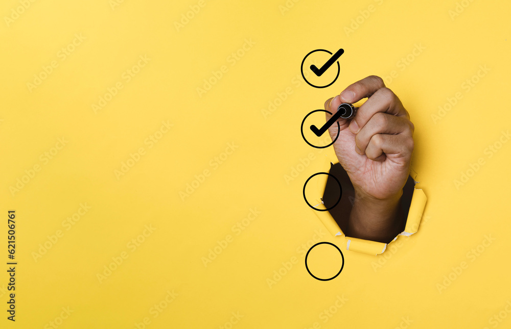 Aufkleber Hand use pen to tick correct sign mark in checkbox on punched yellow paper for quality document control checklist and business approve project concept.