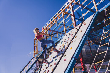 Athletic young woman working out and climbing a ropes at the rope training camp.