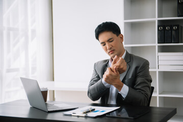 Obraz premium Overworked young Asian businessman office worker suffering from neck pain after had a long day at desk. office syndrome concept