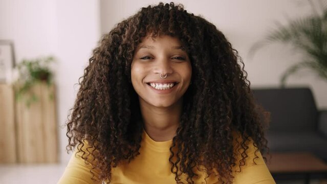 Head shot smiling young african woman looking at camera during video call. Cheerful teenager female listening while having a virtual meeting online. 
