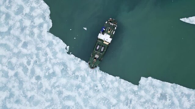 A look from above on a ship cruising between icebergs in the Arctic Ocean by Svalbard.