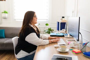Profile of a busy fat woman typing on the computer at the office