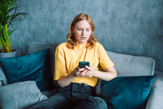 Shocked concerned cellphone user girl staring at screen, looking at smartphone screen, finding problems with online app, poor connection, Internet service, getting surprising bad news. High quality