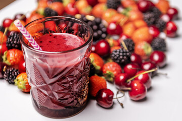 A glass of red berry detox juice with a straw, ripe red