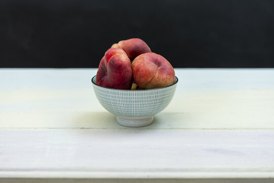 A small blue bowl with a few paraguayas inside