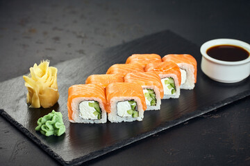 Sushi roll (Philadelphia) with salmon, cucumber, cream cheese on dark background. Sushi menu. Japanese food.