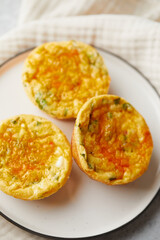 Savory muffins with egg, feta cheese, cheddar and spinach on light background