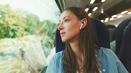 Close up, cute girl with long brown hair, wearing blue shirt, wearing wireless earphone into ear...