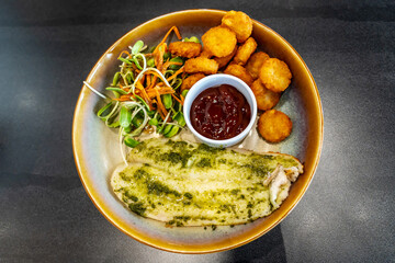 Fried fillet of sea white cod fish with chicken nuggets on a large dish on a table background. Healthy balanced food. Top view