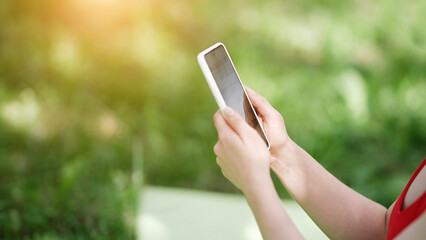 Young woman using smartphone after doing yoga outdoors in the park, sports yoga concept    