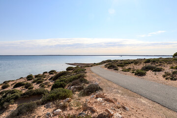 Walking path leading along coastline against blue sky