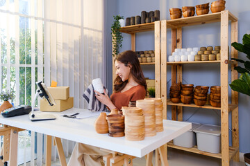 Asian beautiful woman sell vase product online live streaming at home. Young attractive girl clean the goods with rag before showing tho the customers. Remote buying and purchase shopping concept.