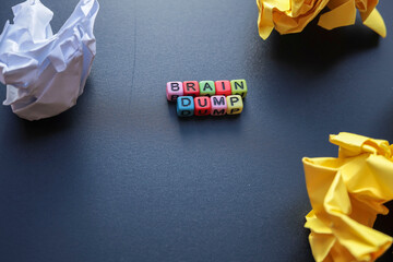 BRAIN DUMP on the black background with crumpled papers. 