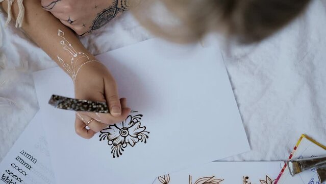 Young woman practice henna or mehndi designs on paper