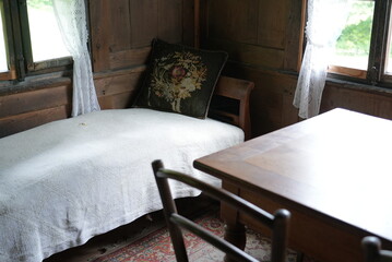 wooden bed frame and table, a bed in a room with a wooden floor and furniture, a small white wooden bed frame, in the style of rural life scenes, the window frame is wooden, in the style of tapestry