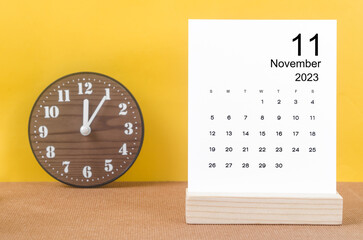 Fototapeta na wymiar The November 2023 Monthly calendar for 2023 year with clock on yellow table.