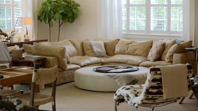 Chic living room adorned with comfy leather couch, round soft table, design armchairs and wooden elements. Country style in modern interior