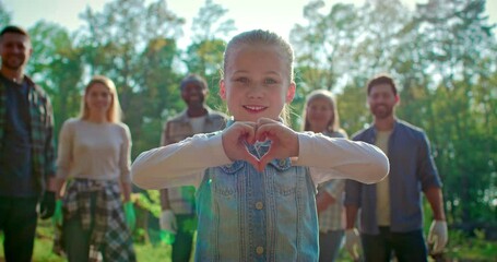 Portrait of little cute girl volunteer standing and showing heart gesture. Joyful child help to save environment. Team of young people for eco friendly help and waste management. - Powered by Adobe
