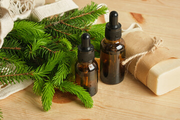 glass amber bottles with pipettes and spruce branches with young needles