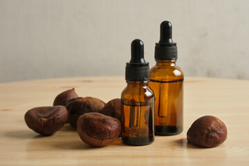 essential oil in amber glass dropper bottle and fresh chestnuts on wooden background
